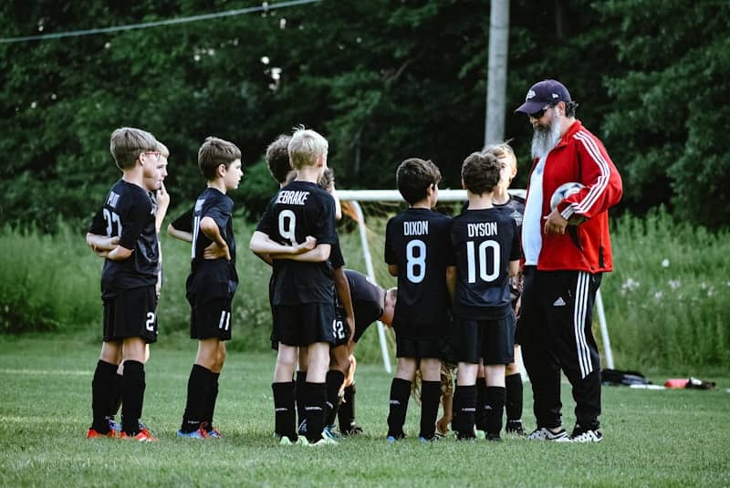 Coach talking to a group of kids in football uniforms